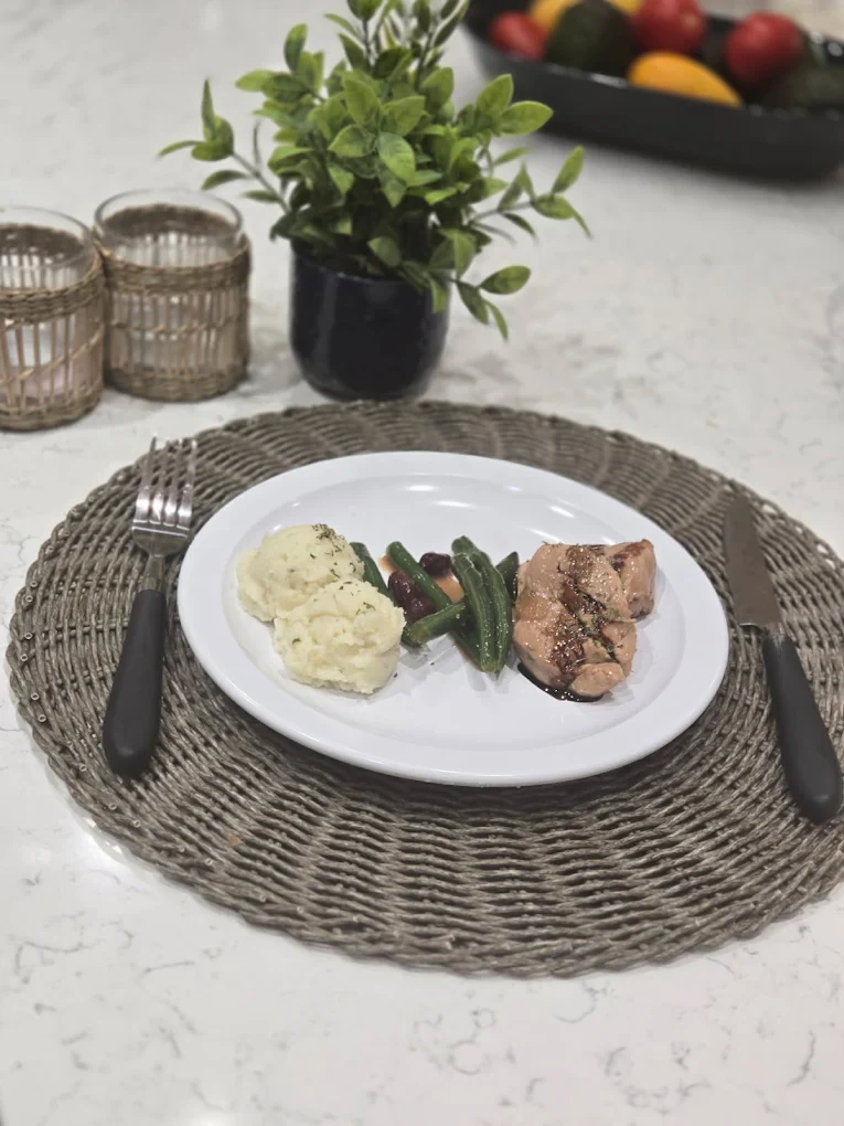 Une assiette de viande, de pommes de terre et de légumes verts sur une table dressée